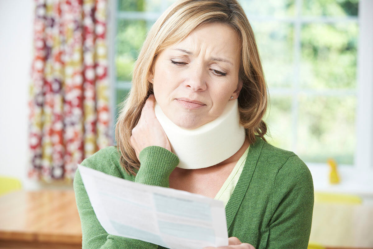 A women in a neckbrace looking unhappy while holding a medical bill