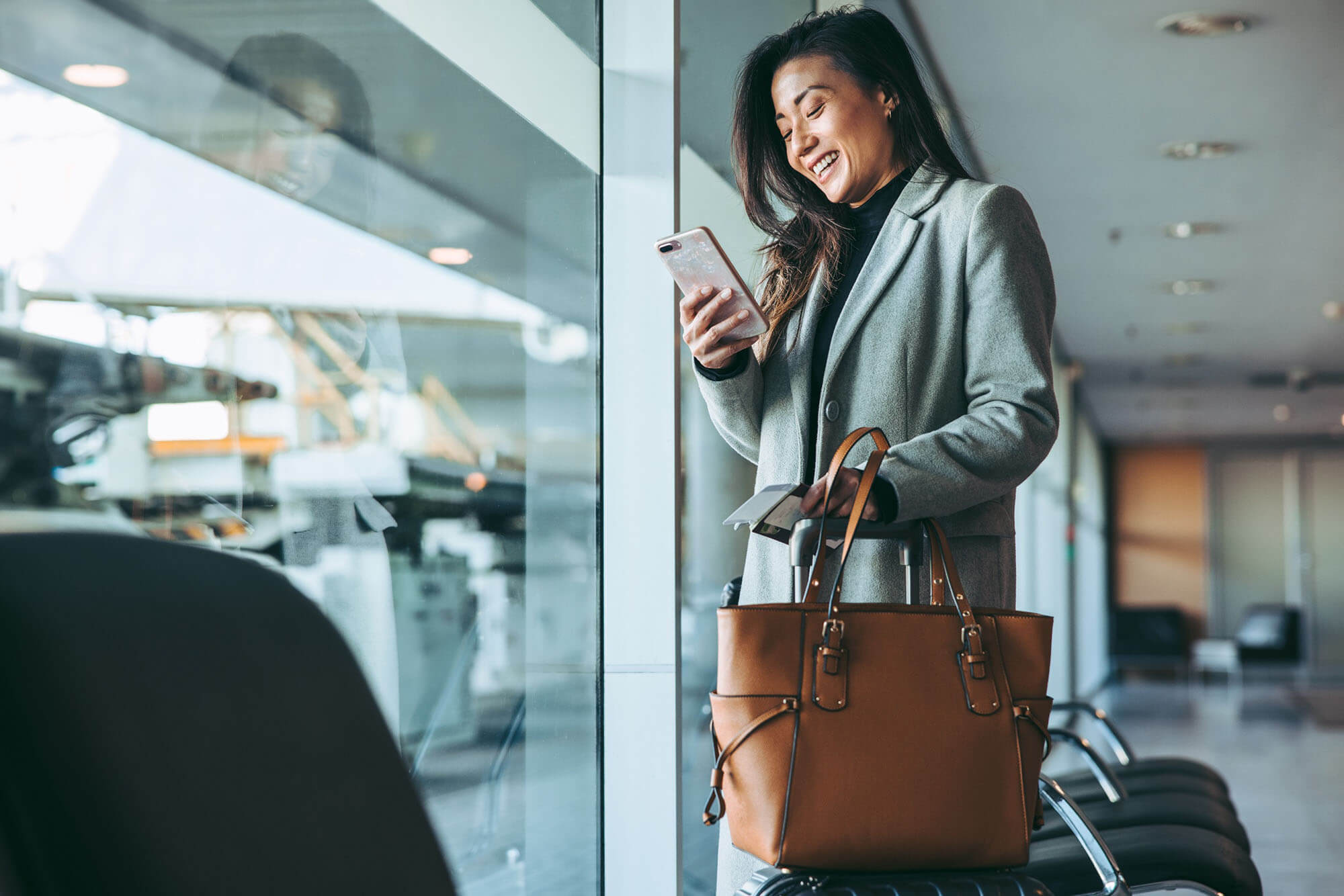 A women in a business suit smilling while looking at her phone